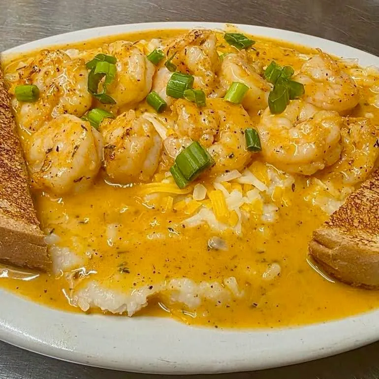 Cajun shrimp over cheesy grits with green onions and toast points